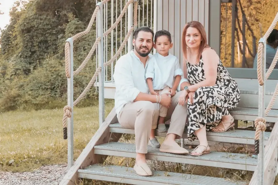 Familienfoto auf Treppe Familie sitzt auf einer Holztreppe, bestehend aus einem Mann, einer Frau und einem kleinen Jungen.