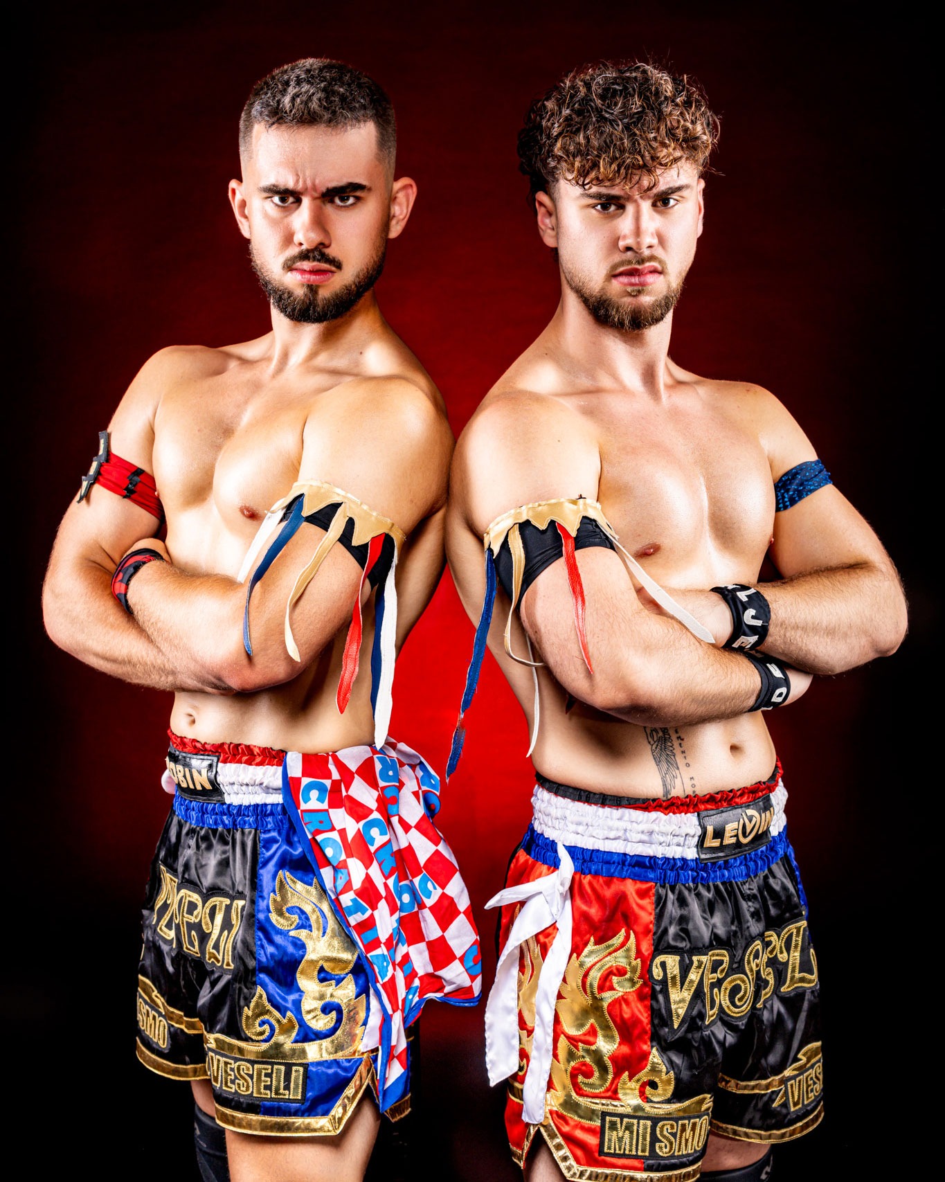 Zwei männliche Kämpfer in Muay Thai Shorts mit verschiedenen Farbbändern an den Armen.